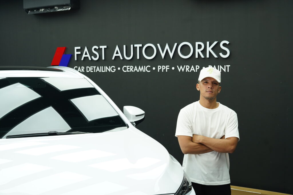 Ian Ebarle, owner of FAST Autoworks Parañaque, standing beside a freshly detailed black car in the new shop.